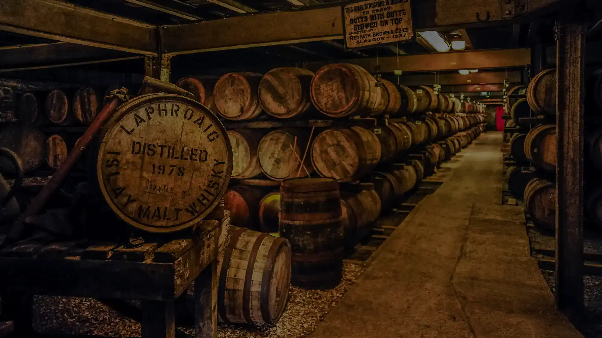 Candlelit whisky warehouse with rows of aging casks in a Scottish distillery